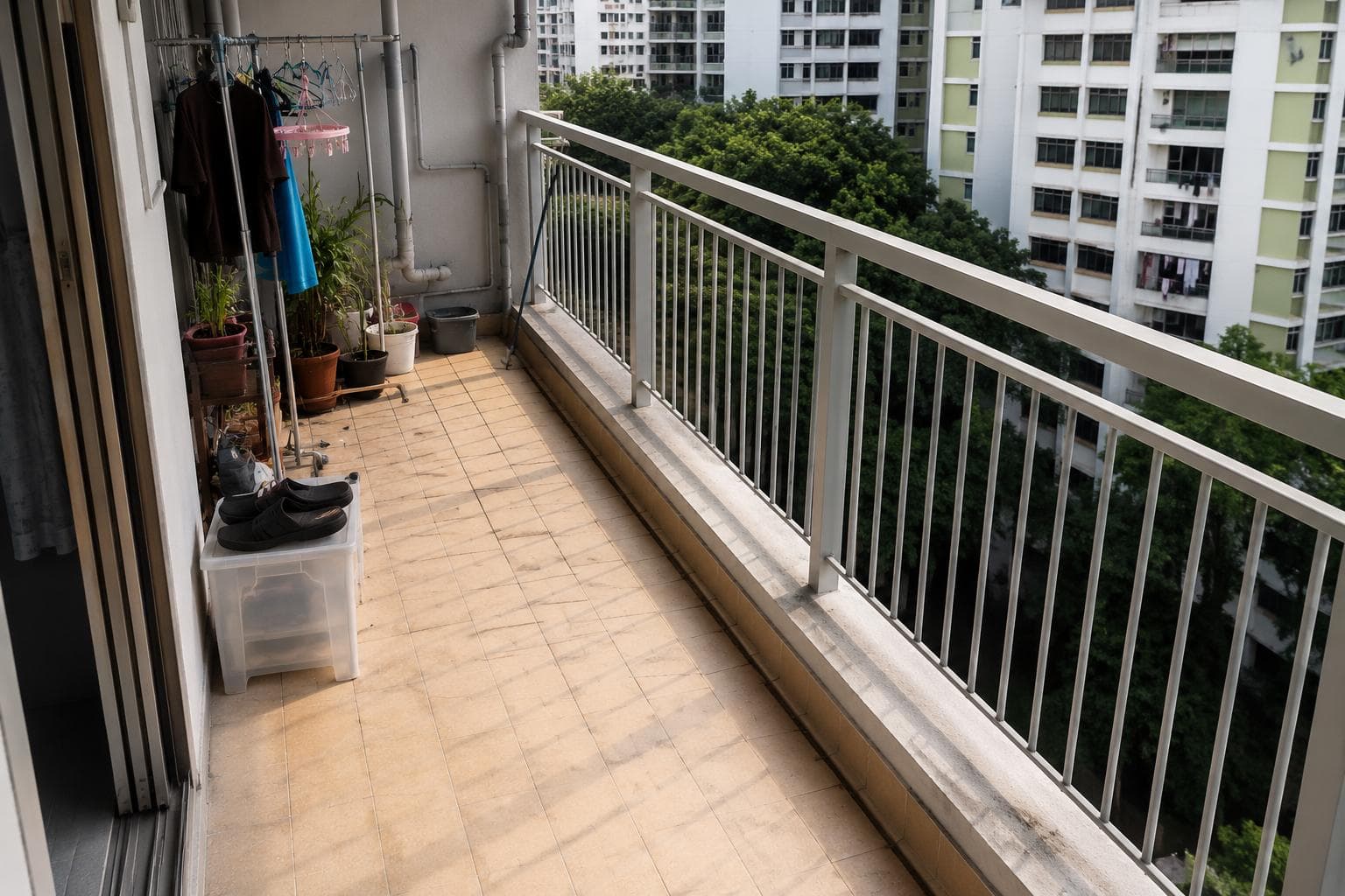 HDB balcony before renovation with tiled floor, laundry rack, and utility clutter